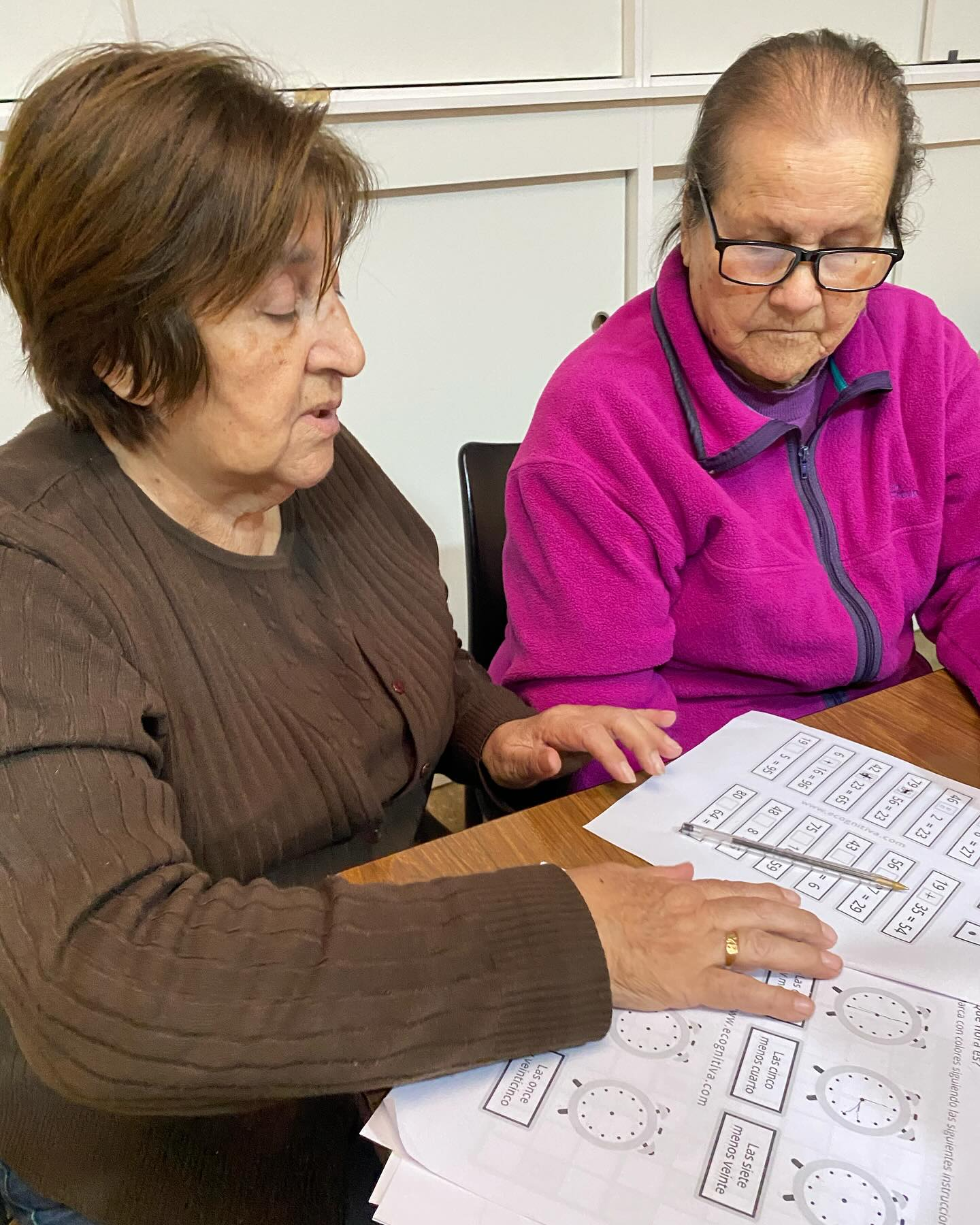 Dos personas mayores realizando actividades cognitivas en el centro de acogida